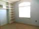 Sunlit bedroom with neutral walls, plush carpeting, a built-in bookshelf, and a bright window at 100 Heatherwood Blvd, Lake Wales, FL 33859