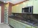 An updated kitchen showcases green cabinets, granite countertops, and stainless steel appliances at 100 Heatherwood Blvd, Lake Wales, FL 33859
