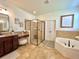 Spacious bathroom features glass shower, soaking tub, and vanity with granite countertops at 1055 Lena Run Ct, Winter Haven, FL 33880