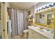 Charming bathroom showcasing a stylish vanity, decorative mirror, and patterned shower curtain for a touch of elegance at 200 El Camino Dr # 202, Winter Haven, FL 33884