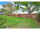 The backyard features green grass, a brick wall, landscaping, and large trees at 208 Lake Region S Blvd, Winter Haven, FL 33881