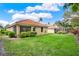 The backyard features green grass, a red tile roof, landscaping, and a brick wall at 208 Lake Region S Blvd, Winter Haven, FL 33881