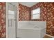 Bathroom featuring enclosed glass shower and soaking tub, floral wallpaper, and window at 208 Lake Region S Blvd, Winter Haven, FL 33881