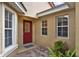 Home entrance with red door, tan stucco, and brick paver landing at 208 Lake Region S Blvd, Winter Haven, FL 33881