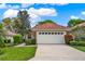 Inviting single-story home featuring a tile roof, lush landscaping, and a spacious two-car garage at 208 Lake Region S Blvd, Winter Haven, FL 33881