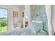 Bright bedroom with light green accents, patterned wallpaper, white armchair, and balcony overlooking picturesque greenery at 2300 N Scenic Hwy # 56, Lake Wales, FL 33898
