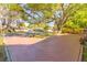 Wide driveway leading to a charming single-Gathering home with a lush, tree-filled front yard at 3027 Maplewood Ave, Lakeland, FL 33803