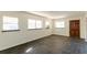 Spacious living room featuring tile flooring, three windows, and a dark wood door at 3027 Maplewood Ave, Lakeland, FL 33803