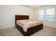 Cozy bedroom with a dark wood sleigh bed and carpet floors, complemented by natural light from the windows at 4004 Prima Lago Cir, Lakeland, FL 33810