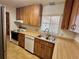 Kitchen featuring wood cabinetry, tile flooring, and a stainless steel sink under a window at 407 Paradise Island Dr, Haines City, FL 33844