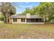 Home's rear exterior featuring a chimney, siding, and screened in porch, and an ample backyard at 4615 Reynosa Sw Dr, Winter Haven, FL 33880