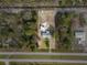 An aerial view showing the home and shed surrounded by treed lot and nearby road at 6261 Red Grange Blvd, Indian Lake Estates, FL 33855