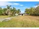 Expansive front lawn showcases this lovely single-story home with a long driveway, mature trees and blue skies at 6261 Red Grange Blvd, Indian Lake Estates, FL 33855