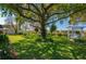 Expansive backyard with a large tree, lush lawn, pergola swing, and landscaping at 633 Hart Lake Dr, Winter Haven, FL 33884