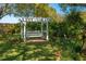 Beautiful backyard featuring a white pergola swing, lush greenery, and manicured lawn at 633 Hart Lake Dr, Winter Haven, FL 33884