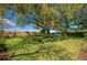 Spacious backyard with lush green grass, mature trees, a pergola and a swing at 633 Hart Lake Dr, Winter Haven, FL 33884