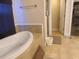 Elegant bathroom featuring a soaking tub, neutral tile, and access to the walk-in closet at 700 E Park Rd, Haines City, FL 33844