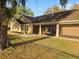 Tan single Gathering home featuring an attached garage and a covered and screened-in porch, perfect for outdoor enjoyment at 700 E Park Rd, Haines City, FL 33844