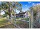 View of the rear of a well-maintained single-Gathering home showcasing the screened in porch and gated yard at 700 E Park Rd, Haines City, FL 33844