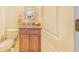 Charming half bathroom with granite countertop, wood cabinets and a decorative mirror at 700 E Park Rd, Haines City, FL 33844