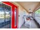 The red front door framed by the screened in porch, featuring multiple rocking chairs at 700 E Park Rd, Haines City, FL 33844