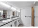 Bathroom with a dual sink vanity, neutral countertop, large mirrors, and storage cabinets at 700 Mirror Terrace Nw # 501, Winter Haven, FL 33881