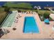 Aerial view of a rectangular pool and shuffleboard court, surrounded by lounge chairs and brick patio at 700 Mirror Terrace Nw # 501, Winter Haven, FL 33881