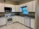 Well-lit kitchen with white cabinets, stainless steel appliances, and stone countertops at 708 E Broadway St, Fort Meade, FL 33841