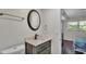 Bathroom with a dark wood vanity, bronze fixtures, round mirror, and view into bedroom at 900 Avenue Z Se # A3, Winter Haven, FL 33880