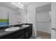 Bathroom with double sinks, black cabinets, large mirror, and neutral walls at 10234 Lenox St, Clermont, FL 34711