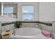 Bright bathroom featuring a large soaking tub, tiled surround, and a window offering natural light at 10234 Lenox St, Clermont, FL 34711