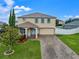 Two-story home with a well-manicured lawn, brick driveway, and attached two car garage at 10234 Lenox St, Clermont, FL 34711