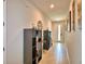 Hallway with light wood-look flooring, display shelving and decor leading to a front door with glass at 1091 Sugarwood St, Davenport, FL 33837