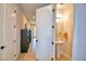 Hallway with open bathroom, display shelving, and light wood-look flooring leading to a front door at 1091 Sugarwood St, Davenport, FL 33837