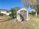 View of the outbuilding with grey doors surrounded by green yard and trees at 11 Sun Air Blvd E, Haines City, FL 33844