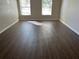 Spacious bedroom with wood-look floors, neutral walls, and plenty of natural light streaming through two windows at 1106 Partridge Way, Kissimmee, FL 34759