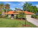 Charming home featuring a red tile roof, lush landscaping, and a well-manicured lawn at 1116 Cypress W Pt, Winter Haven, FL 33884