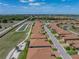 An aerial view displays the community's layout, showcasing the homes, roads, and nearby amenities under a bright sky at 1124 Sawgrass Dr, Winter Haven, FL 33884