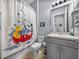 Bathroom with Mickey Mouse shower curtain, gray cabinets, tile floors, and neutral walls at 1124 Sawgrass Dr, Winter Haven, FL 33884