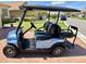 A new looking blue golf cart with black seats sitting on a brick paver driveway at 1124 Sawgrass Dr, Winter Haven, FL 33884