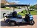 New looking blue golf cart with black seats sitting on a brick paver driveway at 1124 Sawgrass Dr, Winter Haven, FL 33884