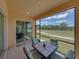 Relaxing screened patio featuring a table with seating, overlooking well-maintained green space and blue skies at 1124 Sawgrass Dr, Winter Haven, FL 33884