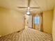 A bedroom showcases a ceiling fan, neutral walls, carpeted floors, and access to a hallway at 114 Jana Cir, Auburndale, FL 33823