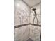 Close up view of remodeled shower with gray veined tiles, black accents, and tiled floor at 151 Lake Ring Dr, Winter Haven, FL 33884