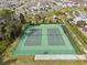 Aerial view of dual tennis courts with green surfaces and full fencing within a residential community at 1744 Cross Prairie Pkwy, Kissimmee, FL 34744