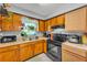 A well-lit kitchen featuring wooden cabinetry, a double sink, and modern appliances for cooking at 210 Pinehurst Dr, Auburndale, FL 33823