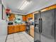 Functional kitchen with wood cabinets, tile flooring, and black appliances including a refrigerator at 210 Pinehurst Dr, Auburndale, FL 33823