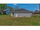 The backyard of a grey home with dark shingle roof and green grass at 225 Babson Dr, Babson Park, FL 33827