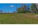 Spacious backyard showcasing green grass, mature trees, and a sprinkler system for easy lawn maintenance at 225 Babson Dr, Babson Park, FL 33827