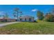 A single-story home with a lush green lawn and mature trees under a clear blue sky at 225 Babson Dr, Babson Park, FL 33827